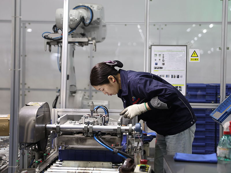 Technician performing battery quality inspection and test analysis at a computer workstation in a clean laboratory